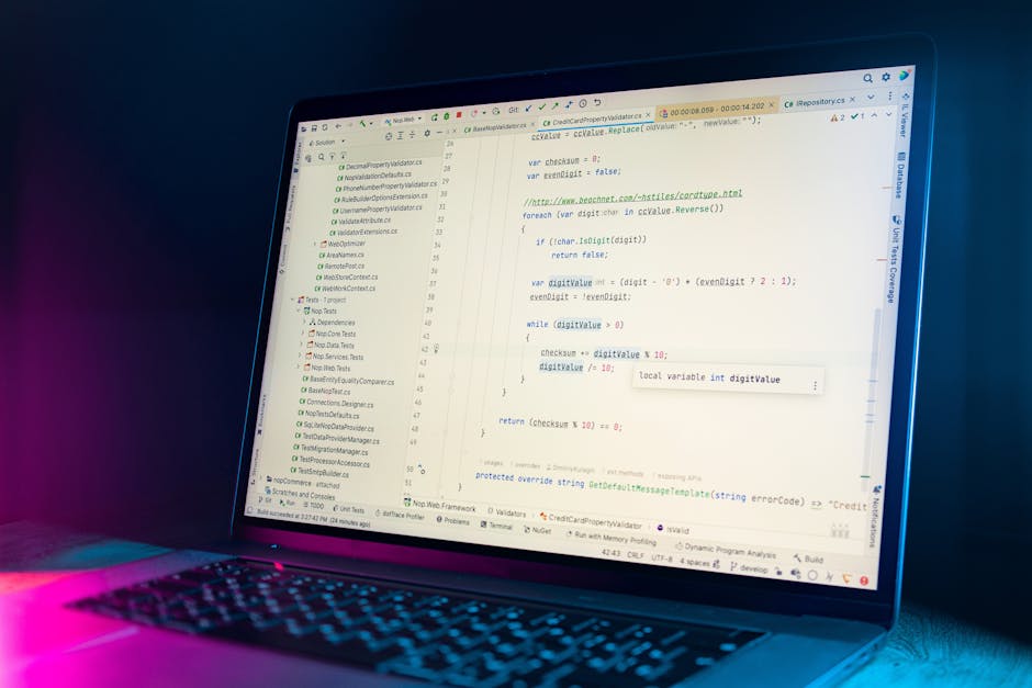 A close-up view of a laptop screen displaying lines of computer code related to software development, with a dark background and illuminated keys. The code features syntax highlighting in various colo
